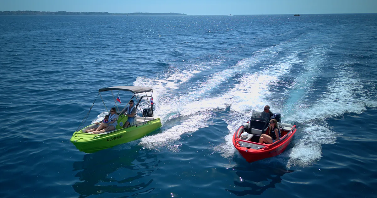 A lime-green and red ROTO Nautica Hydra 460, one of the best boat for beginners, cruising on the sea on a sunny day.